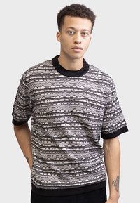 Short-sleeve sweater in black and white with a textured pattern of horizontal lines. Features a ribbed black collar and cuffs.
