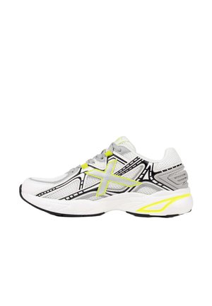 Zapatilla deportiva blanca y gris con detalles en negro y amarillo neón, paneles de malla y suela texturizada, vista de lado.