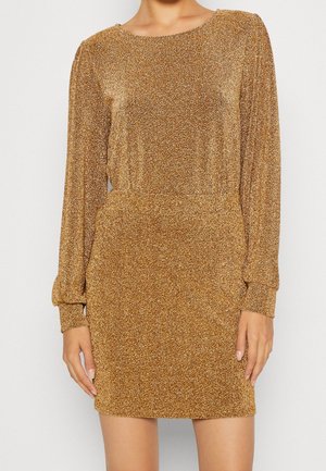 Mini-robe longue manches paillettes dorées avec taille cintrée et encolure ronde portée par une personne debout sur un fond uni.