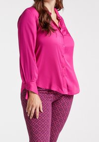 Fuchsia long-sleeve blouse with button front, paired with patterned burgundy leggings featuring a diamond design in pink tones.