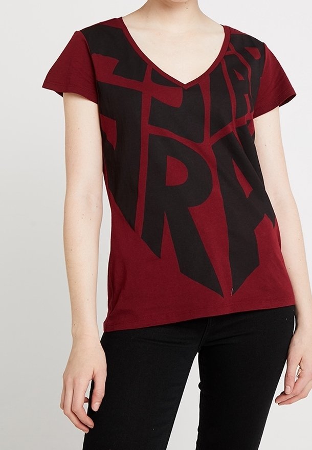 Burgundy t-shirt med v-ringning som har en stor svart grafisk textdesign. Korta ärmar, bomullsmaterial och en avslappnad passform.