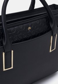 Bolso de mano de cuero sintético negro con herrajes dorados, interior con patrón geométrico texturizado, cierre superior con cremallera y dos asas resistentes.