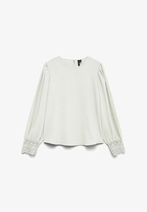 Valge pikkade varrukatega pluus ümarate kaelakaaretega, voltis varrukatega ja pitsist mansettidega, seljal väikese nööpklapiga.