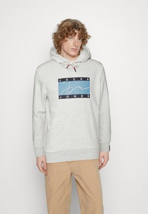 Grå sweatshirt med hætte, prydet med et blåt og sort grafisk logo på forsiden. Materialet er blødt; den har en kengurulomme og snøre.