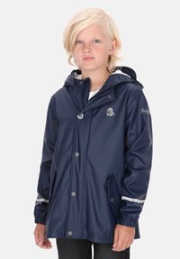 Tamsiai mėlynas nepralaidus vandeniui švarkas su gobtuvu, priekiniais spaudimo mygtukais, dviem šoninėmis kišenėmis ir atspindinčiomis juostomis ant rankovių, pagamintas iš lygios medžiagos.