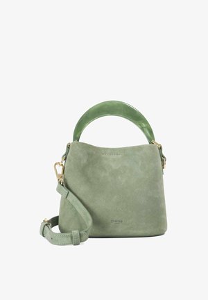 Groene suède handtas met gebogen jadegroene handvat en afneembare schouderriem, gouden hardware en subtiel merklogo aan de voorkant.