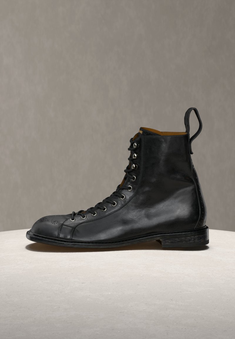 Schwarzer hoher Lederstiefel mit Schnürsenkeln, Zuglasche an der Ferse und Brogue-Details an der Spitze, vor neutralem Hintergrund präsentiert.