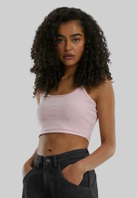 Rosa cropped tank top laget av glatt stoff, med rund hals og brodert logo. Kombinert med høy midje mørk denim jeans.
