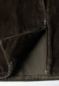 Brązowa kurtka z cordurowego materiału z zamkiem błyskawicznym, z pionowym prążkowanym teksturem, wyposażona w miękką podszewkę i gładki metalowy zamek.