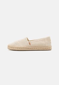 Chaussures espadrilles beige à enfiler avec dessus en tissu tissé et semelle en corde de jute. Présentent un design simple avec une finition texturée.