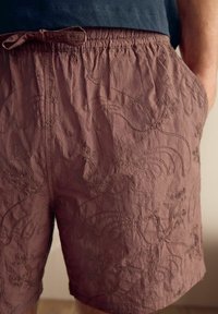 Ruske broderte shorts med en teksturert finish. Har et elastisk liv og snor, prydet med sirkulære blomster mønstre.