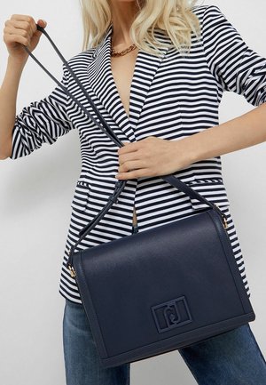 Navy leather handbag with a structured shape, featuring a textured finish and a logo detail. Adjustable strap and gold hardware accents.