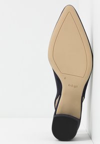 Chaussure à talon haut en daim bleu marine avec bout pointu et semelle extérieure en caoutchouc beige ; marquage embossé sur la semelle ; découpes élégantes sur les côtés.