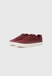 Bordeauxfargede semskede sneakers med lav profil, flat snøring, rund tå og hvit gummi såle. Diskret merkevare på siden.