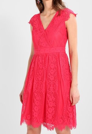 Robe rouge sans manches en dentelle avec col en V, taille cintrée et motifs floraux, longueur mi-cuisse.