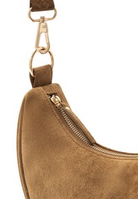 Sac à bandoulière en suède marron à la forme arrondie, doté d'une fermeture éclair et d'accents en métal doré. Surface texturée pour un détail tactile.