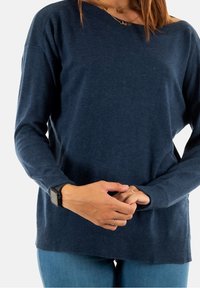 Mörkblå långärmad tröja med lös passform. Har en ribbad halsringning och manschetter, tillverkad av ett mjukt, strukturerat tyg.