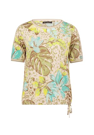 Chemise beige à manches courtes avec grands motifs floraux et feuilles turquoise et jaunes, encolure ronde et détail de cordon de serrage sur le côté.