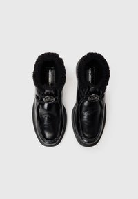 Bottes en cuir noir avec une tige texturée, un col en fourrure, un accent avec un logo rond et des semelles épaisses en caoutchouc noir.