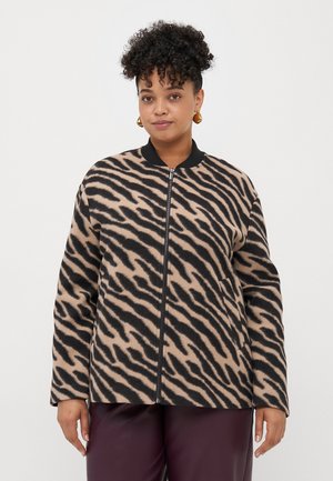 Fleecejakke med zebra-mønster i brune og svarte farger, med glidelås, ribbestrikket krage og to sidelommer. Myk tekstur og avslappet passform.