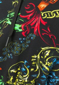 Tessuto nero con vivaci motivi floreali e paisley in rosso, verde, blu e giallo; presenta un cordoncino al collo.