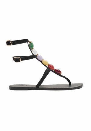 Flad sort sandal med ankelremme og flerfarvede ovale perler langs T-remmen på hvid baggrund.