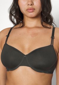 Black underwire bra with smooth, matte fabric. Features decorative bows on straps and a central embellishment above the cup.