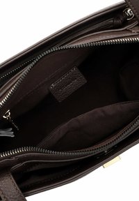 Interieur van een bruin leren handtas, met een gladde textuur, een met rits afsluitbaar vak en een donkere stofvoering. Inclusief een klein merklabel.