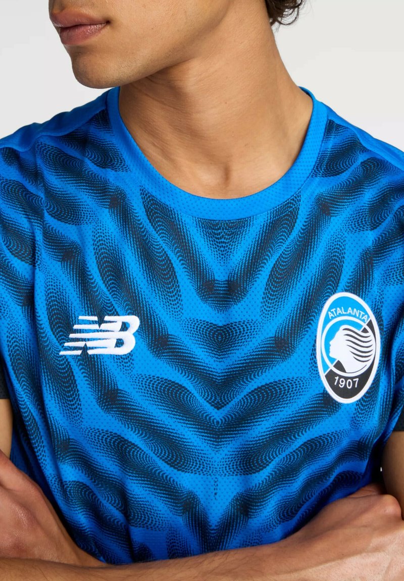 Maglietta atletica blu con motivo a onde nere, collo rotondo e logo bianco sul petto sinistro con emblema circolare.