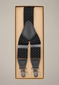 Czarne szelki z białym, diamentowym wzorem, wykonane z elastycznego materiału, z elementami ze skóry i metalowymi klipsami, zapakowane w kartonowe pudełko.