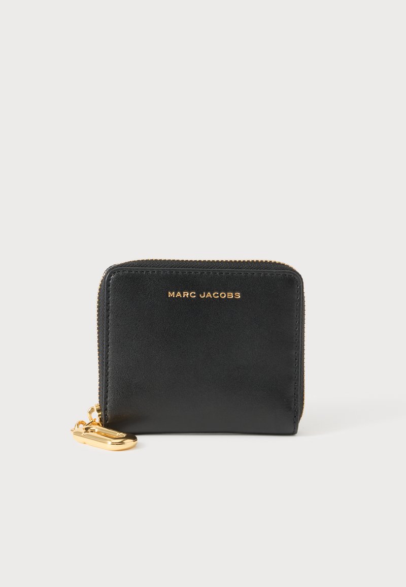 Μαύρο δερμάτινο πορτοφόλι Marc Jacobs με χρυστό φερμουάρ και λογότυπο, με ένα χρυσό κλιπ μπρελόκ σε λευκό φόντο.