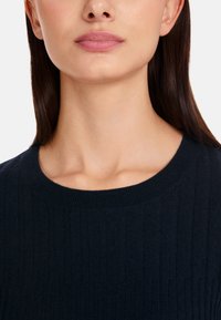 Dunkelblauer, gerippter Strickpullover mit rundem Ausschnitt, enganliegender Passform und glatter Textur. Keine sichtbaren Verzierungen.