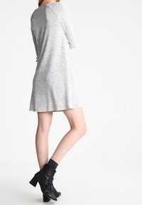 Grå stickad klänning med avslappnad passform, med långa ärmar och rundad nederkant. Matchad med svarta ankelboots och mörka strumpor.