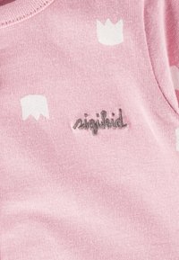 Helles rosa Baumwollhemd mit weißen Kronenmuster. Mit grauem, gesticktem Logo "sigikid" auf der Vorderseite. Weicher, strukturiertes Material.