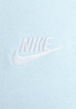 Tejido azul claro con un logo de Nike bordado en blanco. La textura parece suave con un sutil patrón de punto.