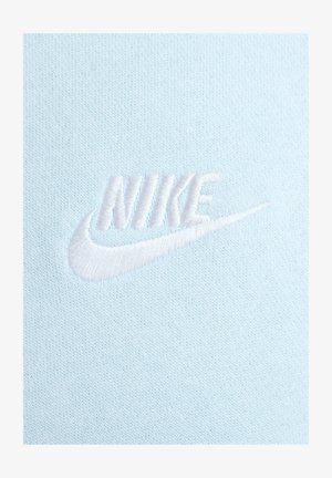 Tejido azul claro con un logo de Nike bordado en blanco. La textura parece suave con un sutil patrón de punto.