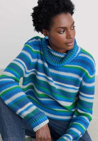 Pulover rayat în culorile albastru, verde și alb; prezintă un guler înalt cu nervuri și manșete. Asortat cu blugi închiși la culoare. Textură de tricot neted.