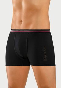Black boxer briefs made of soft fabric, featuring a contrast striped elastic waistband and logo printed on the thigh.