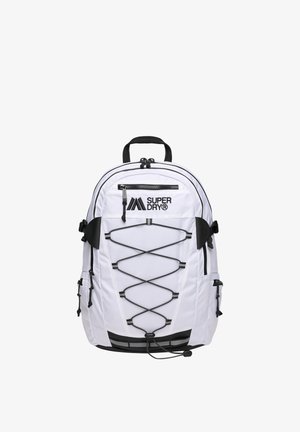Biały plecak Superdry z czarnym zamkiem błyskawicznym, przednim elastycznym sznurkiem bungee, bocznymi kieszeniami i górnym uchwytem do noszenia na jednolitym tle.