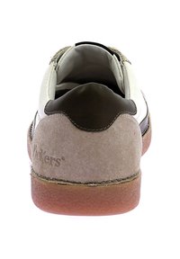 Zapatilla ligera con parte superior de cuero blanco, talón de ante beige, detalles en marrón oscuro y suela de goma texturizada. Presenta un logo en el talón.