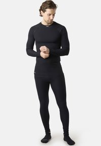 Black thermal base layer set made of ribbed fabric, featuring a long-sleeve top and fitted leggings with a snug fit and stretchability.