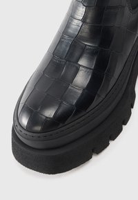Black leather ankle boot with croc-embossed texture, rounded toe, black rubber sole, and slight platform for added height.