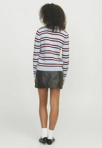 Maglione azzurro chiaro con strisce rosso scuro, polsini a costine, abbinato a una mini gonna in pelle nera, con orlo dritto e vista posteriore dell'outfit.