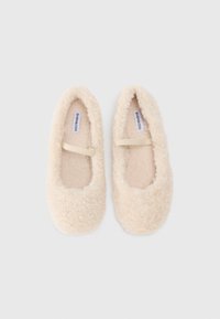 Fuzzy cream-colored slippers with a rounded toe and a flat sole. Features a soft, fluffy texture and an elastic strap across the instep.