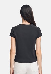 Svart kortärmad skjorta med rund halsringning och raglanärmar, tillverkad av ett mjukt, slätt material, med en figurnära design.