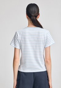 T-shirt a maniche corte a righe blu e bianche, realizzato in tessuto morbido, con scollatura rotonda e una vestibilità rilassata, vista dal retro.