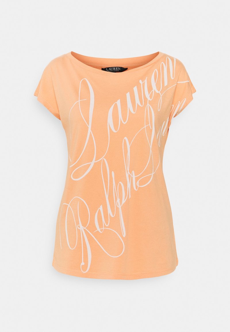 Persikofärgad t-shirt, korta ärmar, rund halsringning, med stora vita kursiva bokstäver. Mjukt bomullsmaterial, avslappnad passform.