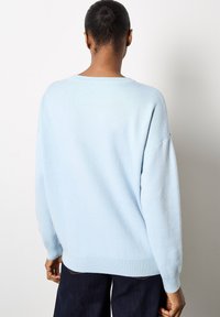 Sudadera de gran tamaño de color azul claro con dobladillo y puños acanalados, que presenta una textura suave y lisa y costuras de hombro caídas.