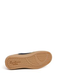 Suela negra de zapatilla con una suela de goma marrón claro, que presenta un patrón de banda de rodadura y el logo en relieve "Pepe Jeans London". Diseño plano y redondeado.