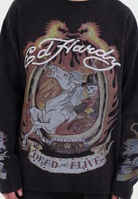 Zwarte sweatshirt met lange mouwen, featuring een grafisch ontwerp van een paard, een skelet en vlammen. De tekst zegt "Ed Hardy" en "DEAD or ALIVE."